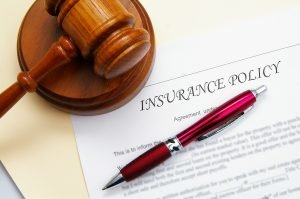 Image of an insurance policy paperwork with a pen and a gavel. 