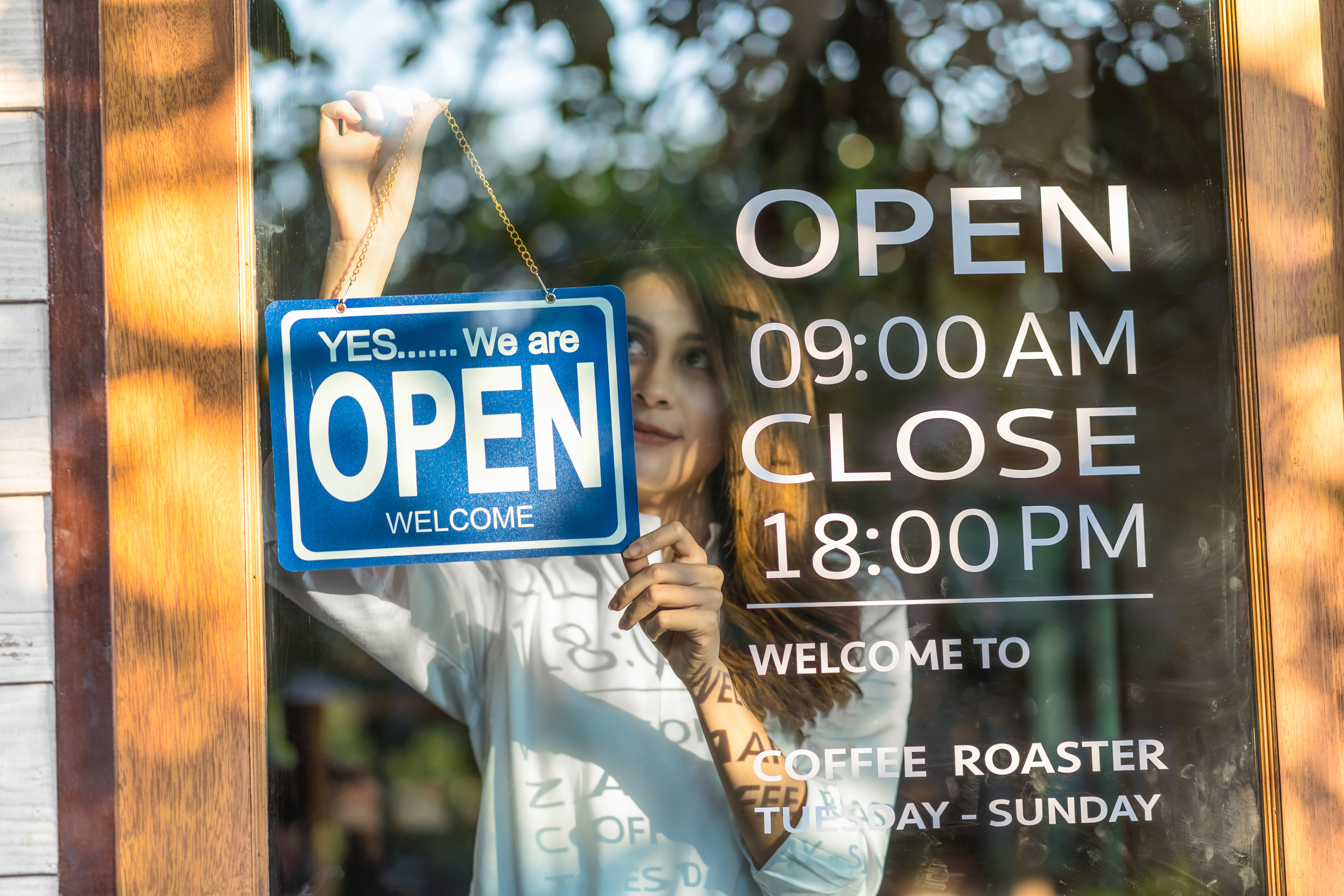 Closeup young woman setting open sign at the shop glasses for welcome the customer in to the coffee shop, small business owner and startup with cafe shop, installing open and close concept