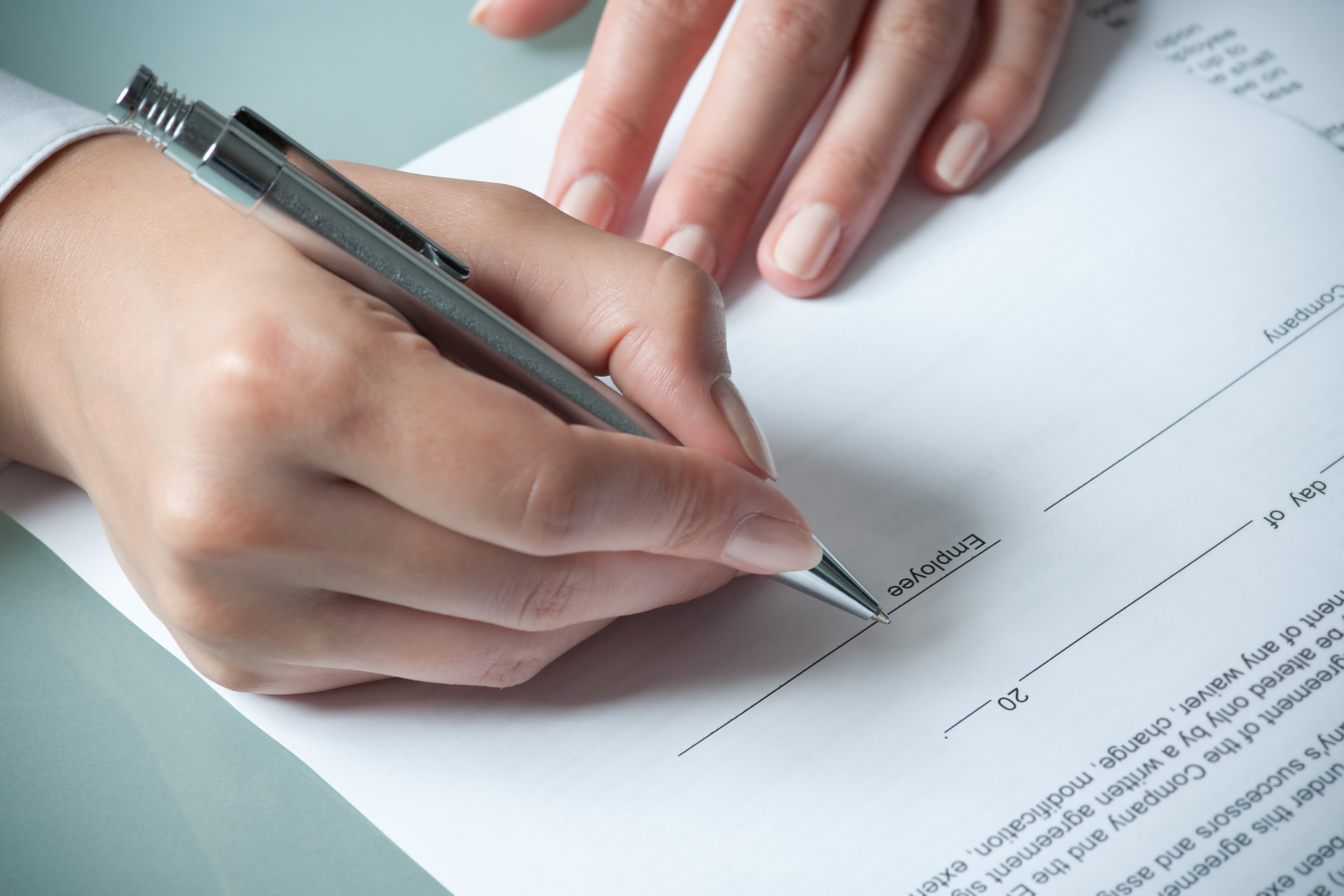 Female hands filling out an employment agreement contract symbolizing changes in Virginia employment law. 