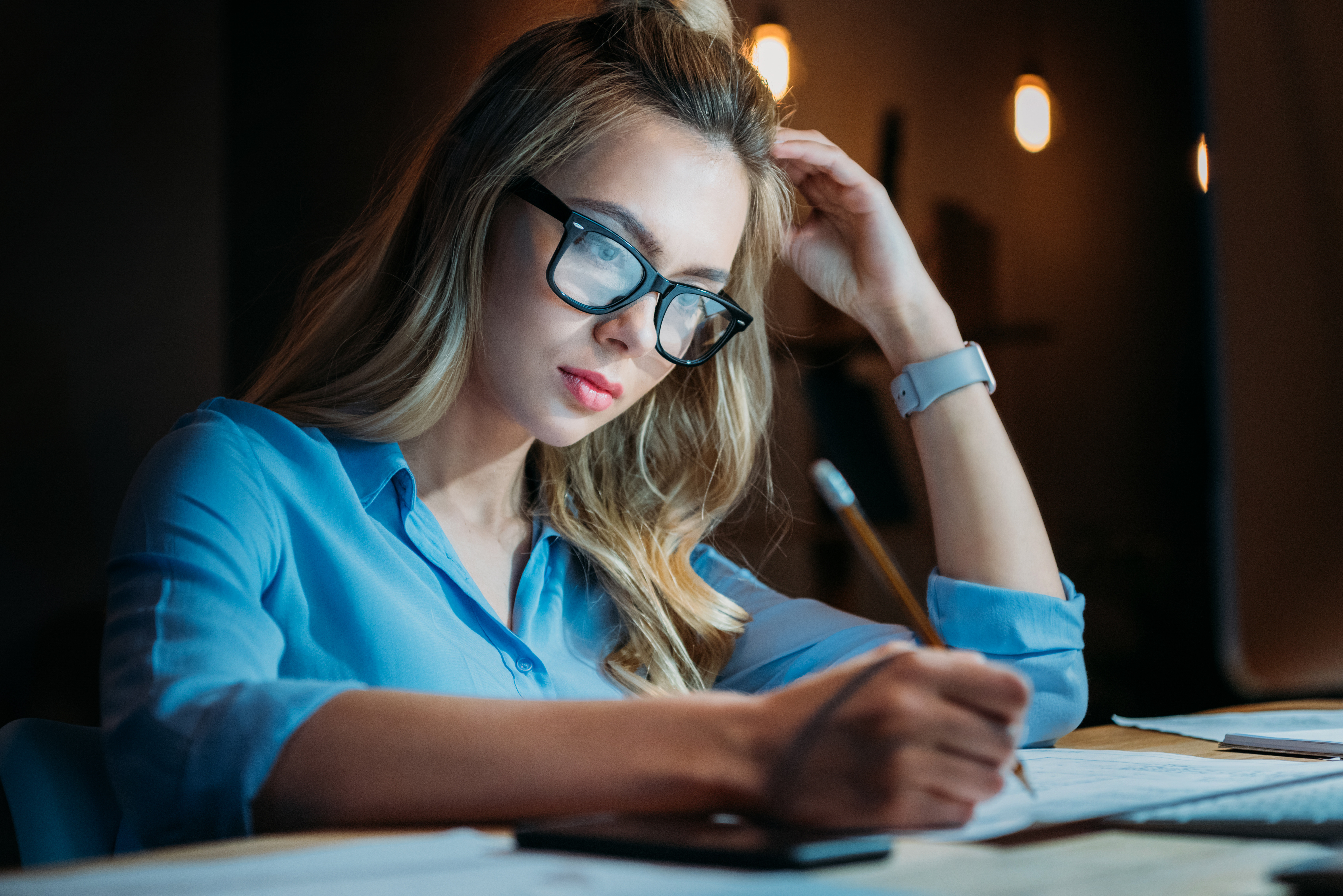 Young female college student with glasses studying for a test late at night. 