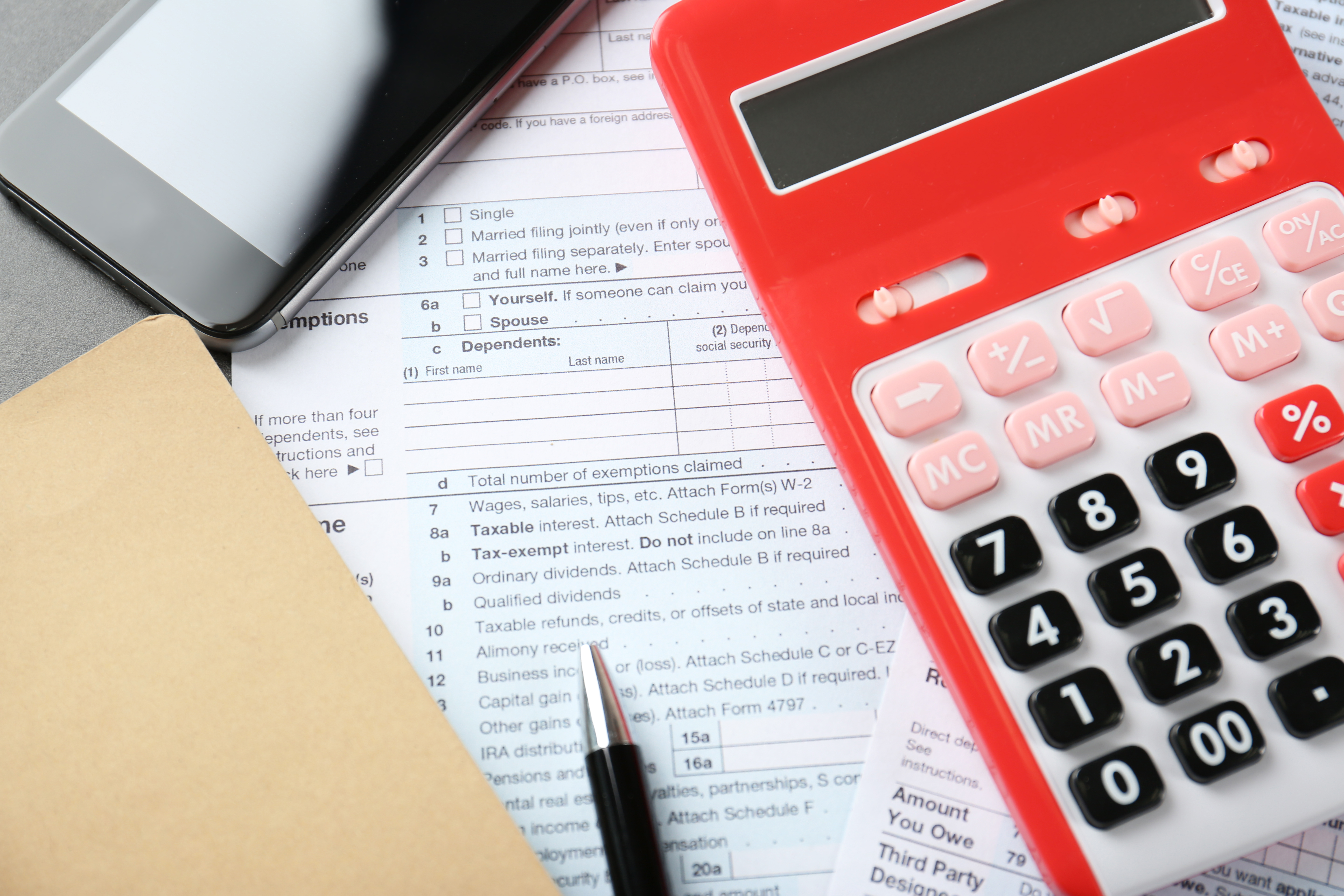 Calculator with documents and cellphone on table representing Maryland personal property tax return.