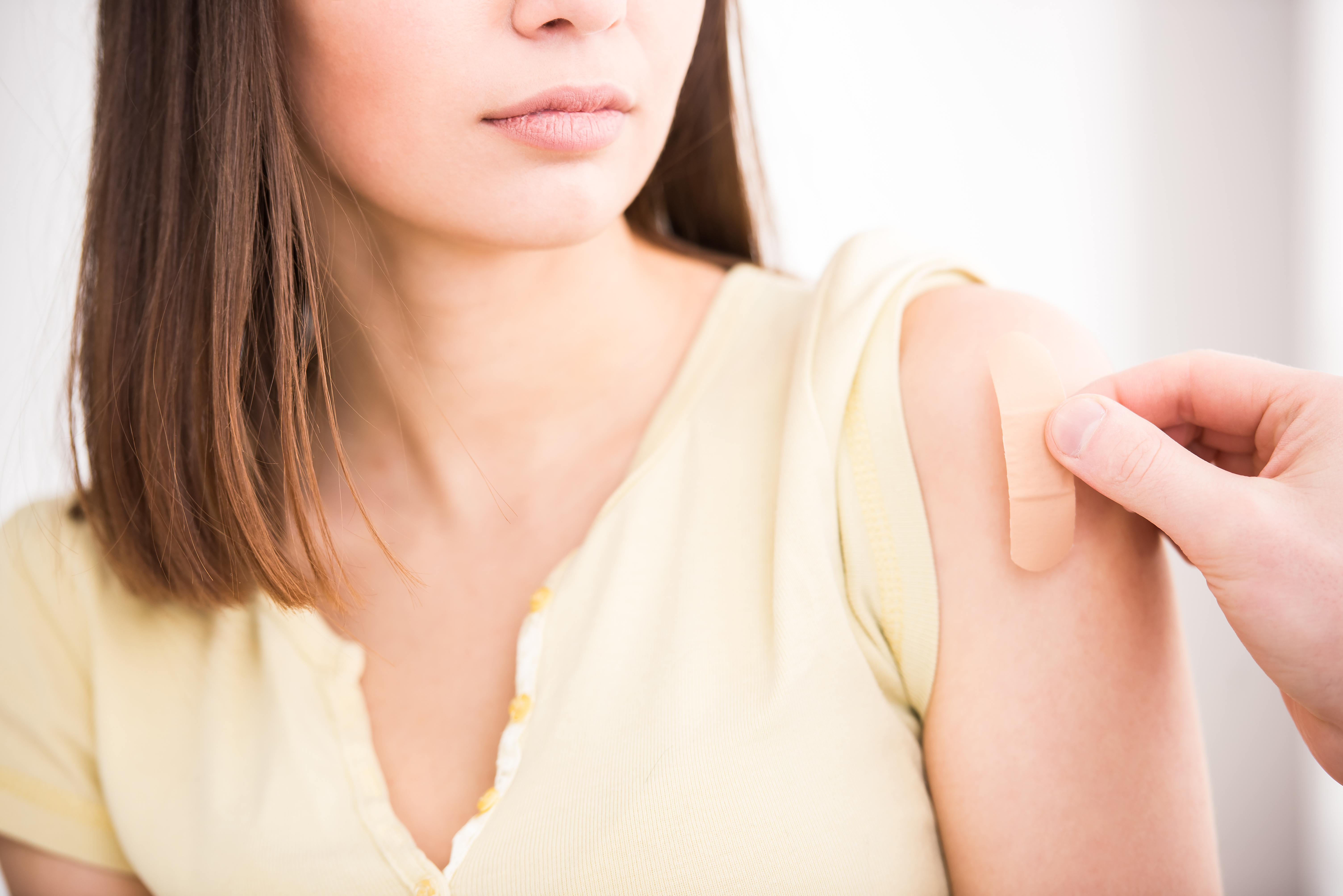 Young woman with bandaid on her arm symbolizing her getting the COVID-19 vaccine. 