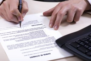 A man is signing a power of attorney, focus is on the tip of the pen. 