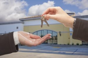 Agent handing over keys to empty commercial building representing a commercial lease. 