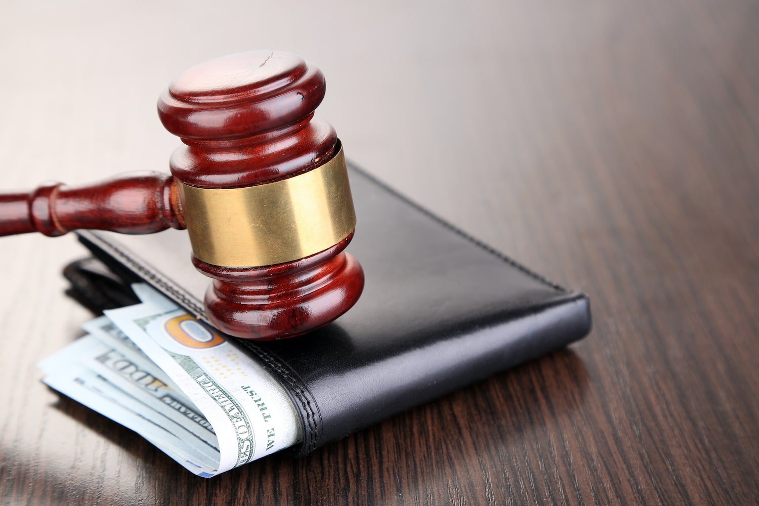 Image of a gavel on top of a wallet with money representing employee wages.