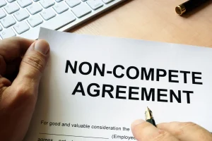 Image of a person holding a piece of paper that says "Non-compete agreement".