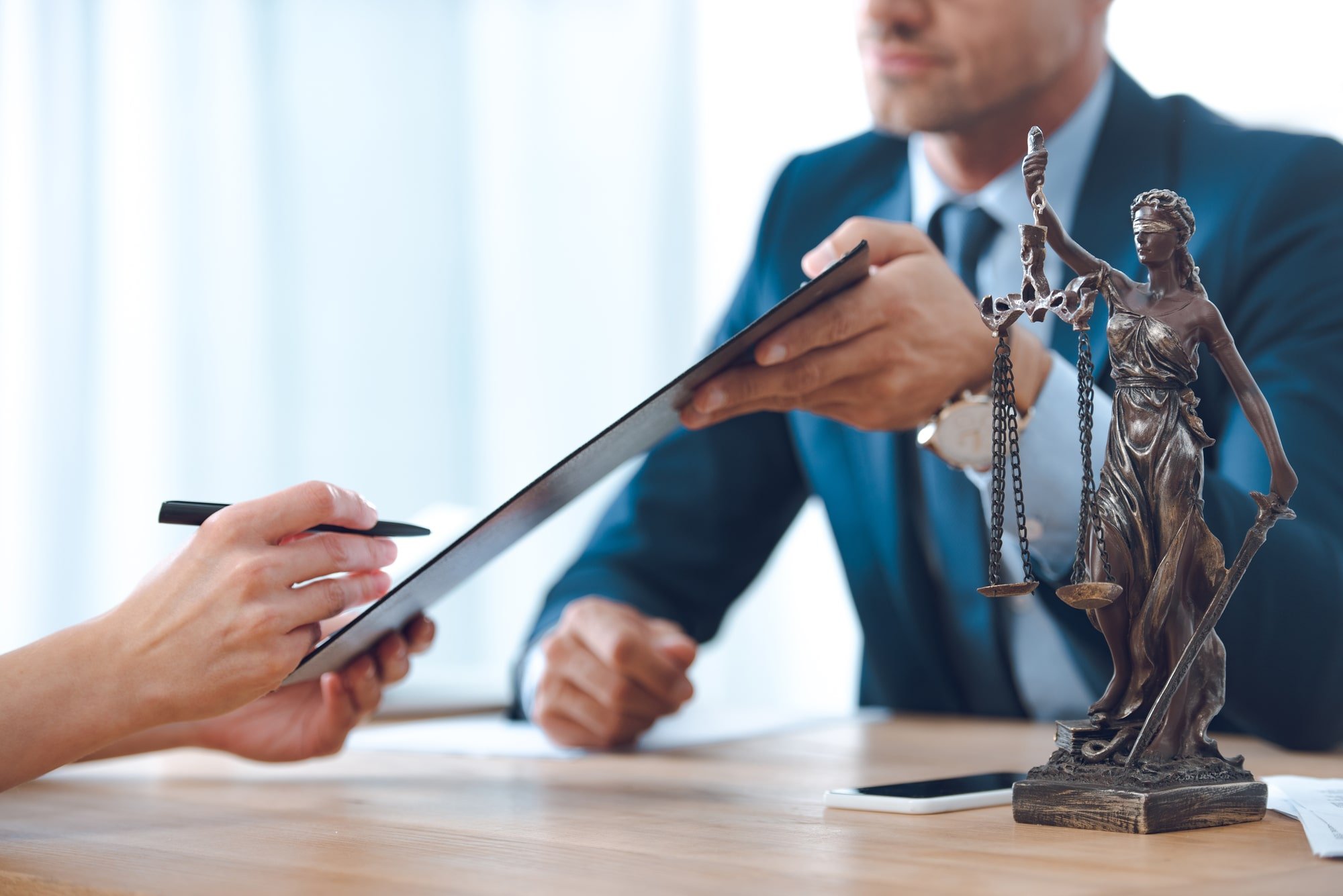 Image of a person signing a legal document with an attorney.