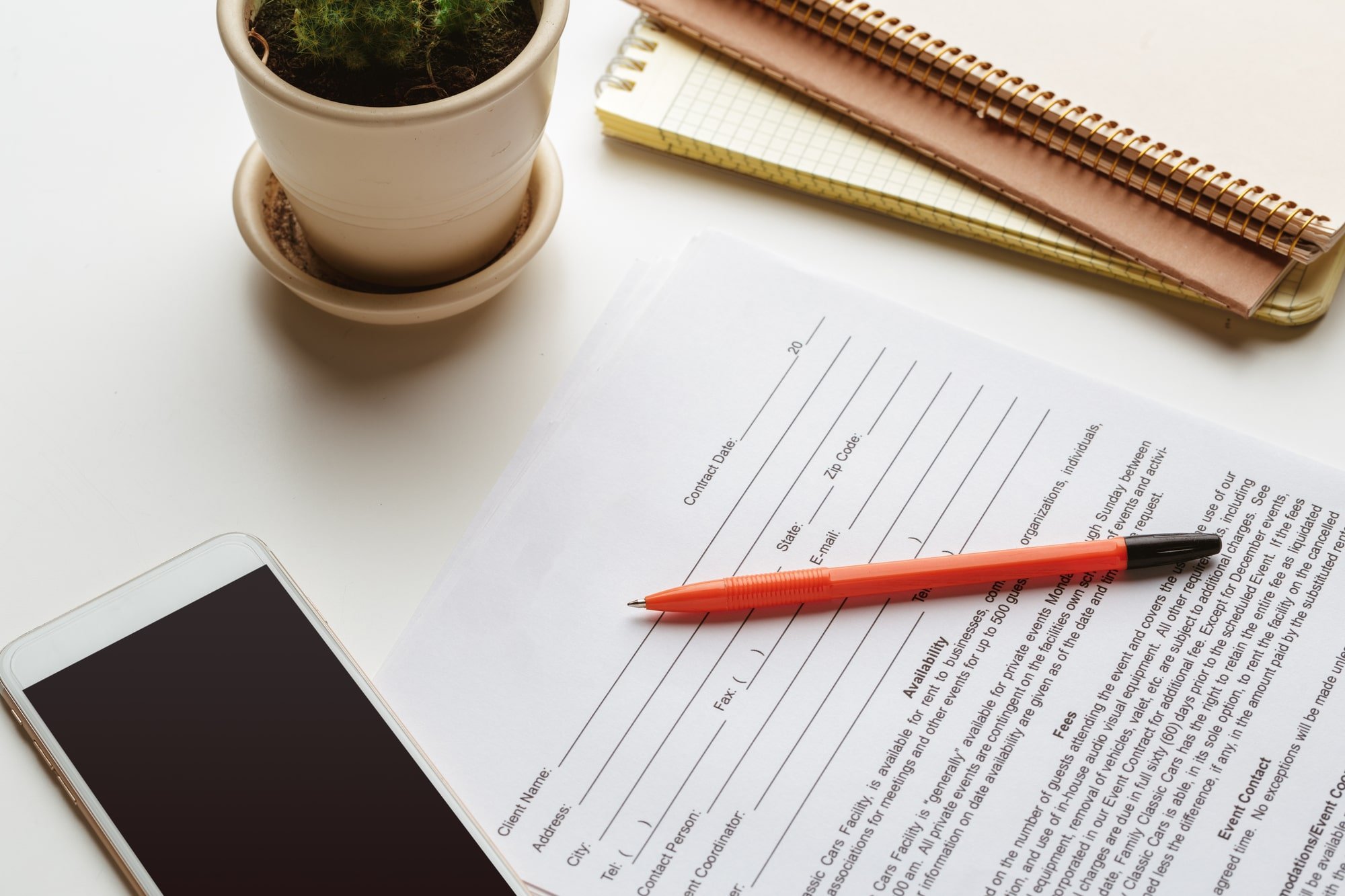  Image of a legal buy-sell agreement on a desk with a mobile phone, plant and notebooks.