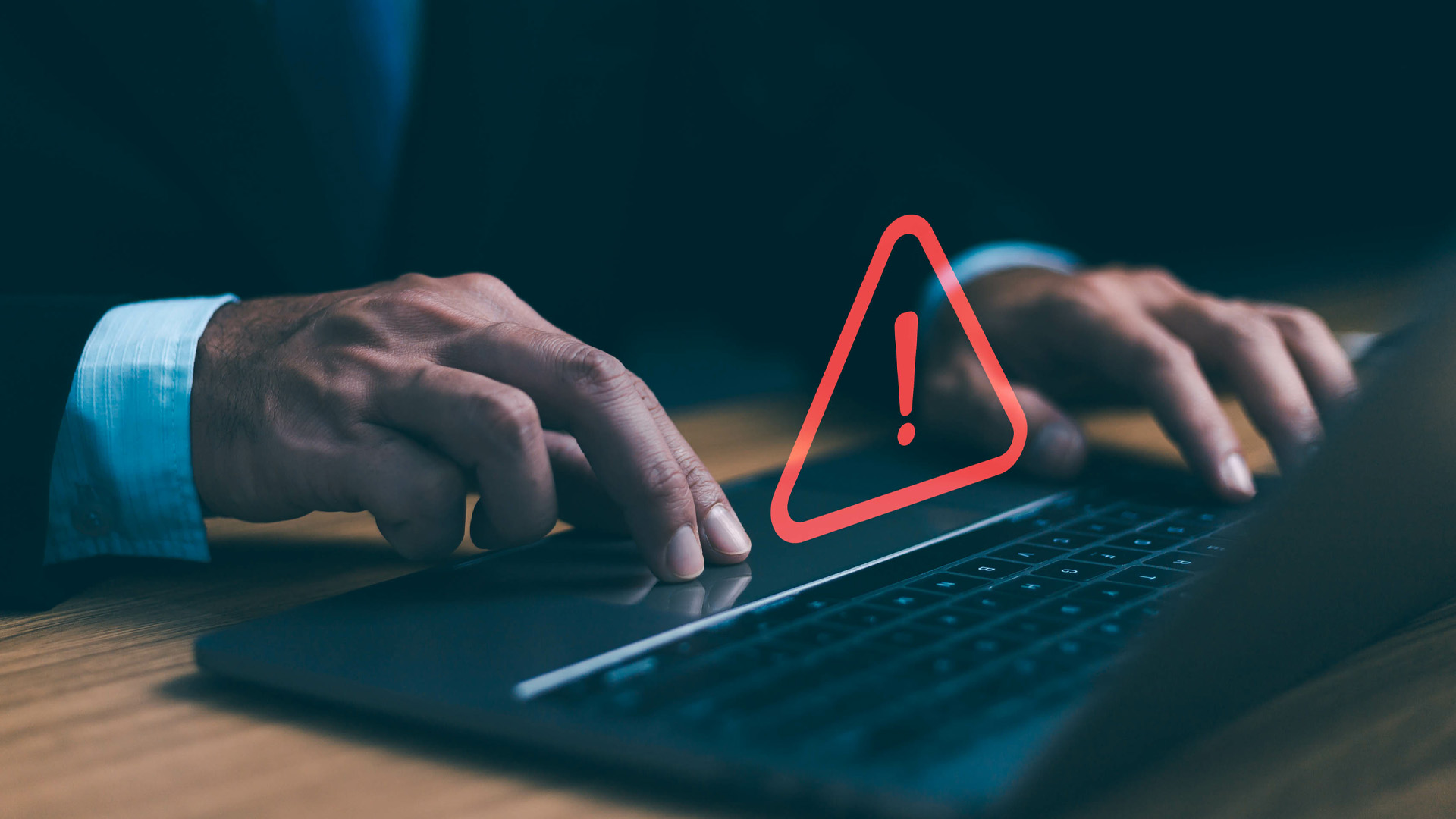 Important update symbolized by a business man's hands typing at a computer with a floating red alert button